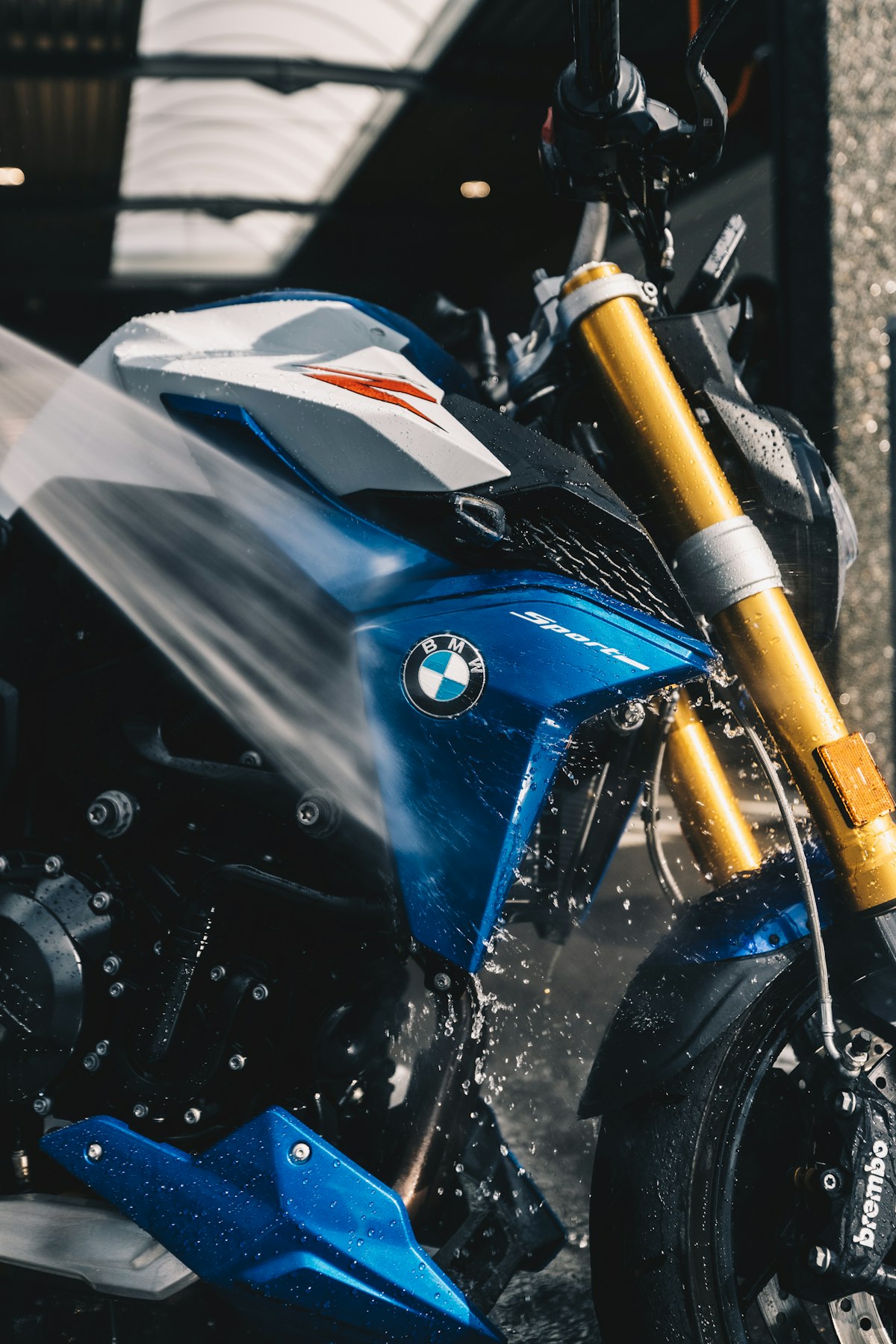 A water jet hitting the fairing of a blue motorcycle