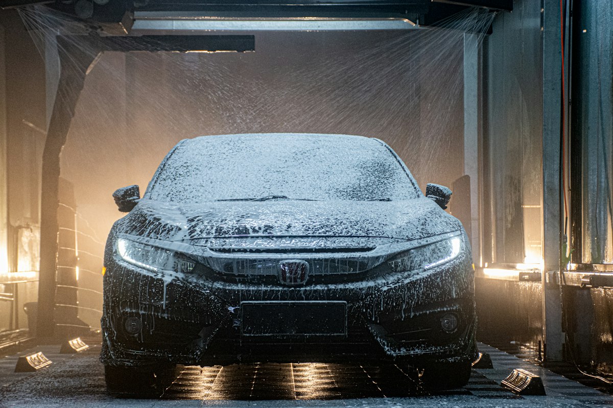 A black car covered in foam in a wash bay