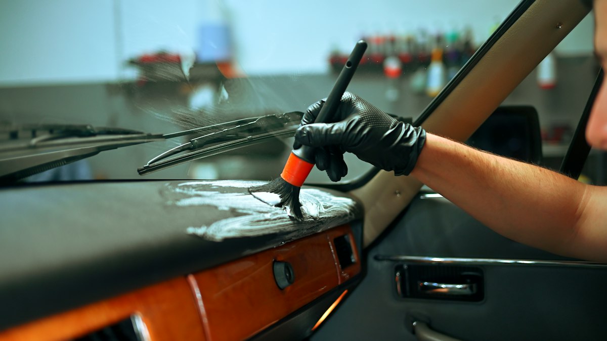 A gloved hand brushing the dashboard of a car